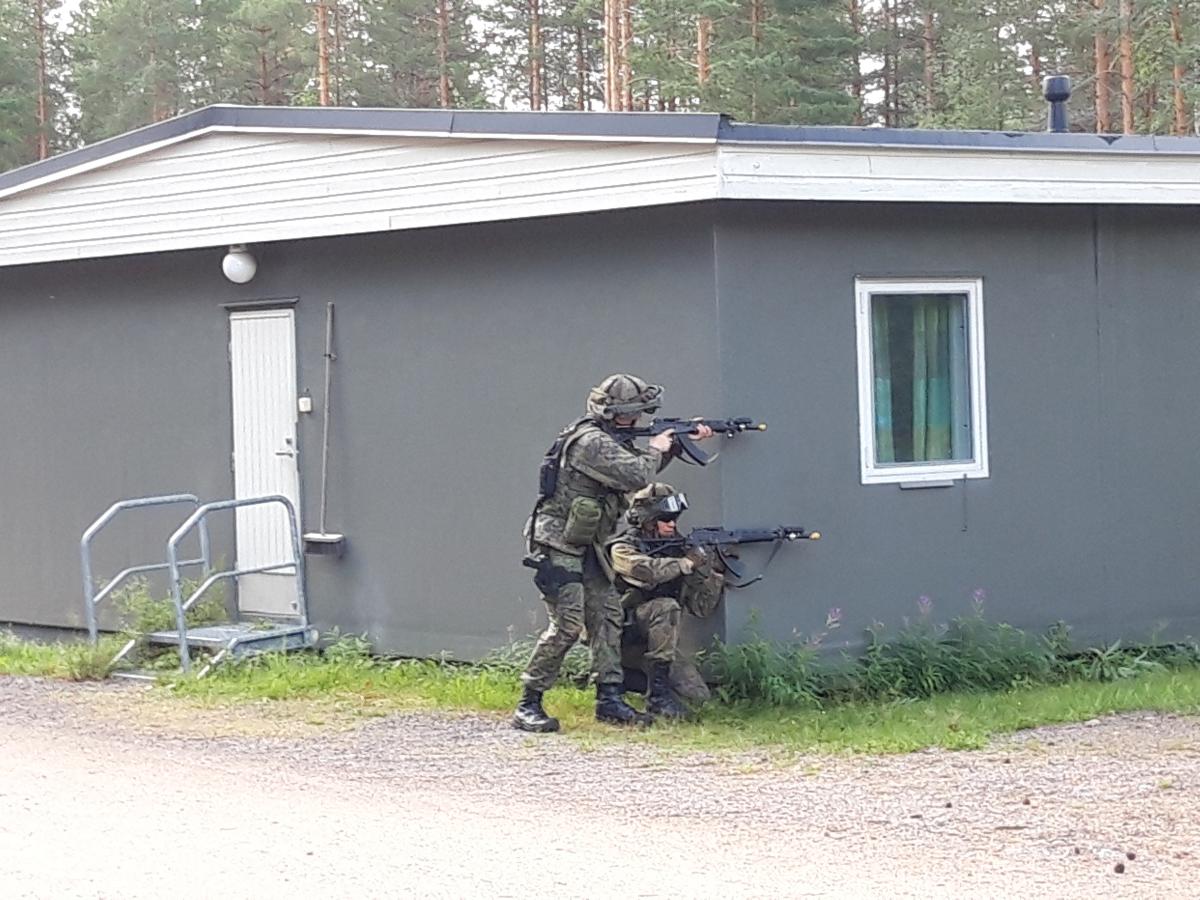 Kuvassa kaksi sotilasta tähtää rynnäkkökivääreillä rakennuksen nurkalla sotilaspoliisien kertausharjoituksessa elokuun lopussa 2021 Etelä-Karjalassa.