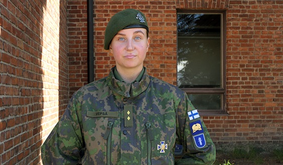 Maastopukuinen sotilas, Aino Vepsä, vihreä baretti päässään katsoo kameraan.