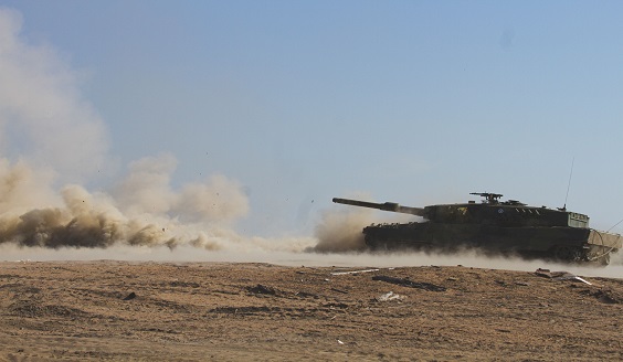 Leo A6 tulitoiminnassa ja hiekka pöllyää.