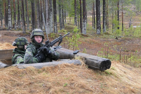 Varusmies taisteluhaudassa rynnäkkökiväärin kanssa jalkaväkiammunnoissa. Märkä keli...