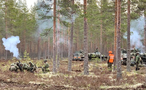 Maastossa sotilaat ampuvat kranaatinheittimellä, heitin savuaa.