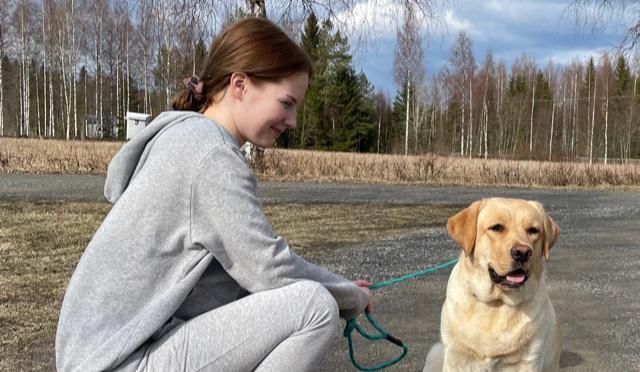 Vaaleahiuksinen nainen katsoo kameraa ja hymyilee.