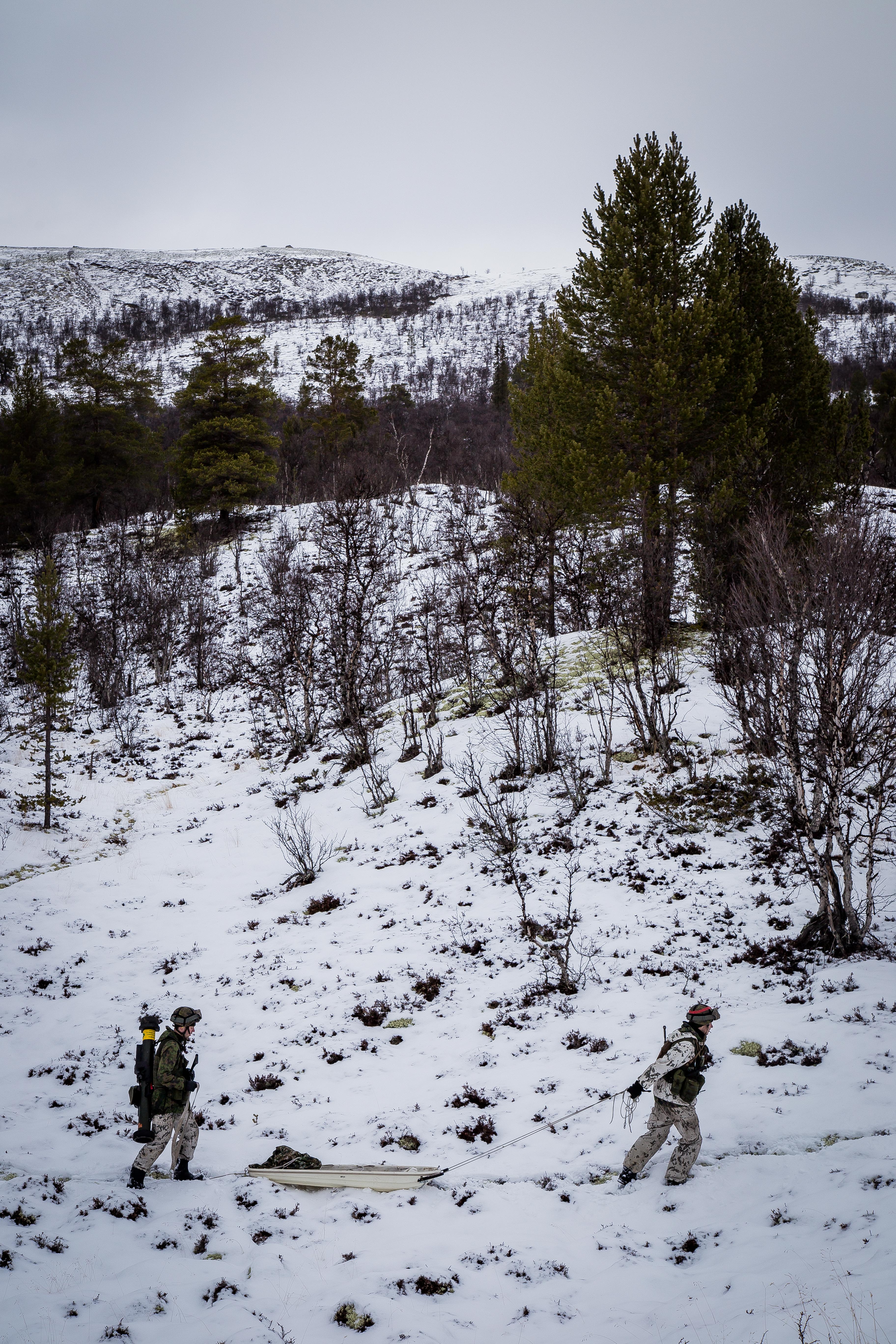 Soldier pulling a sled and a snowy landscape on the background