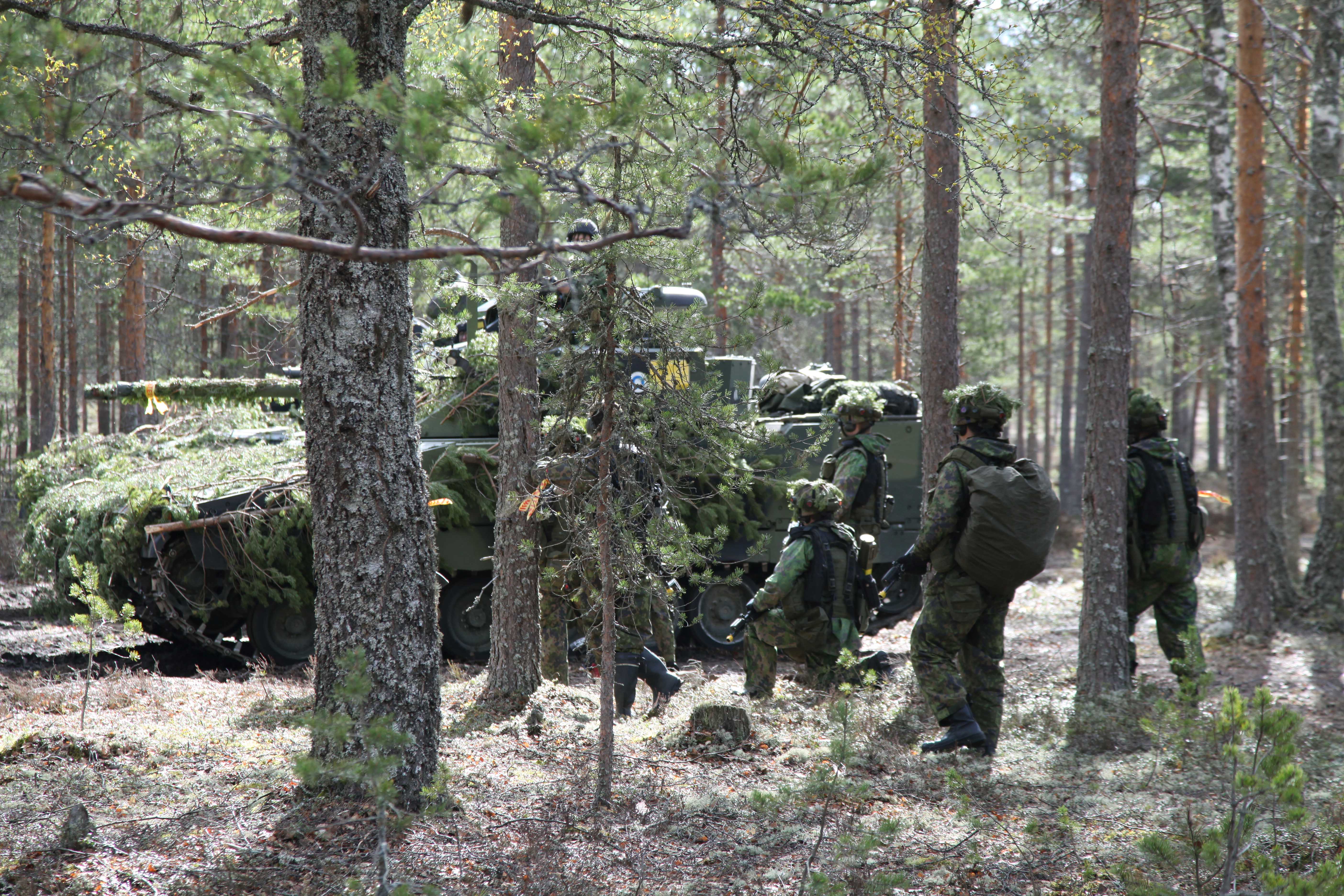 Panssarivaunu ja sotilaita metsässä