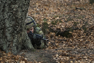Urheilukoulun varusmies tähtää aseella ampumaharjoituksessa.
