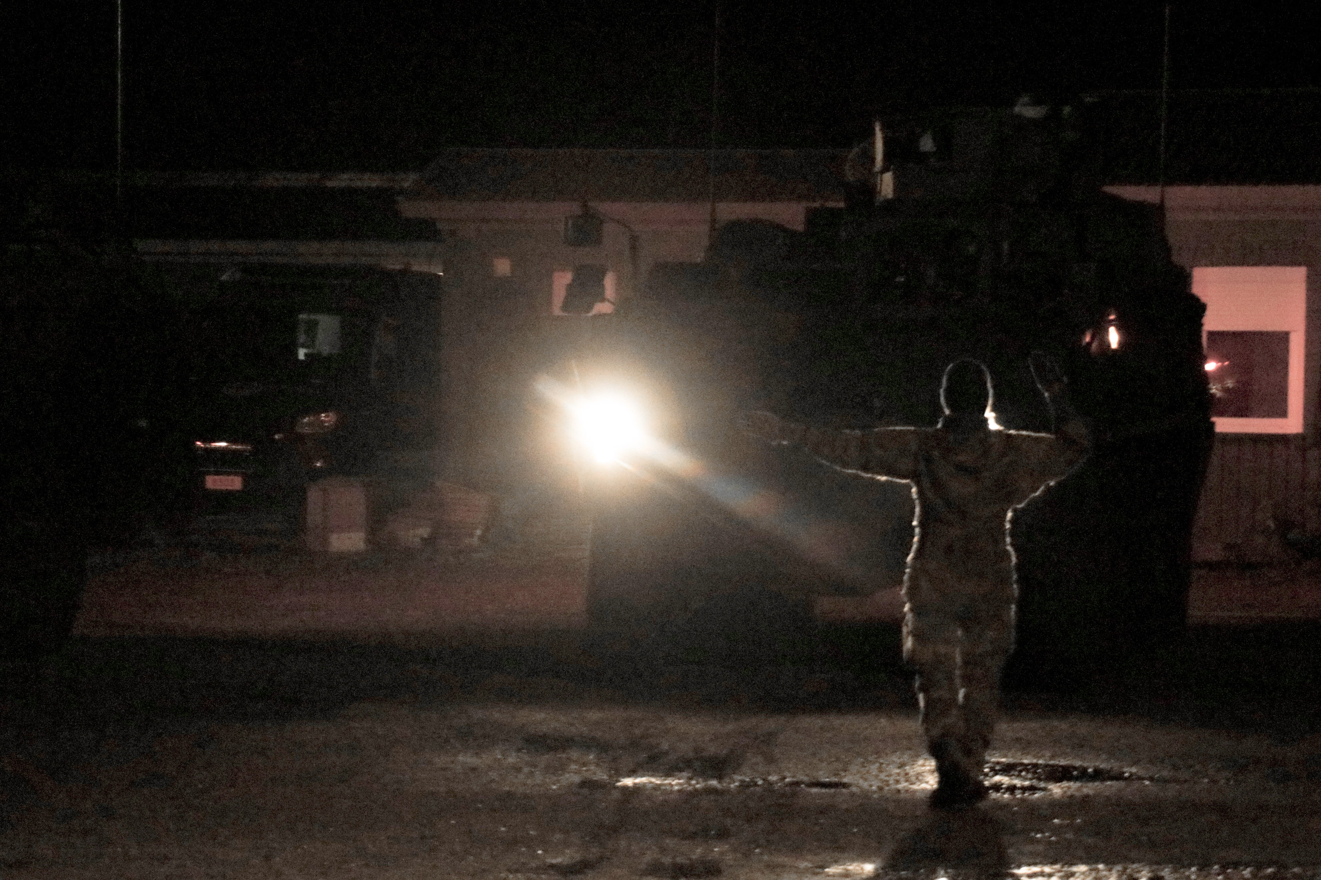 Tanskalainen sotilas opastaa käsimerkein ajoneuvoa pimeässä illassa.