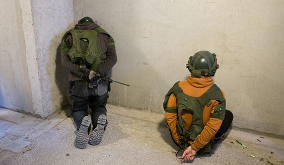Two persons put next to a wall hands tied with zipties