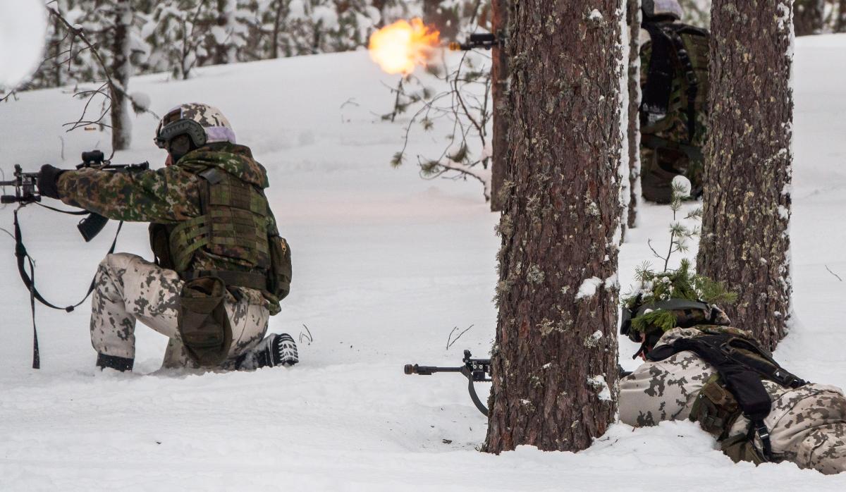 Varusmiehiä taisteluvarustuksessa metsässä.