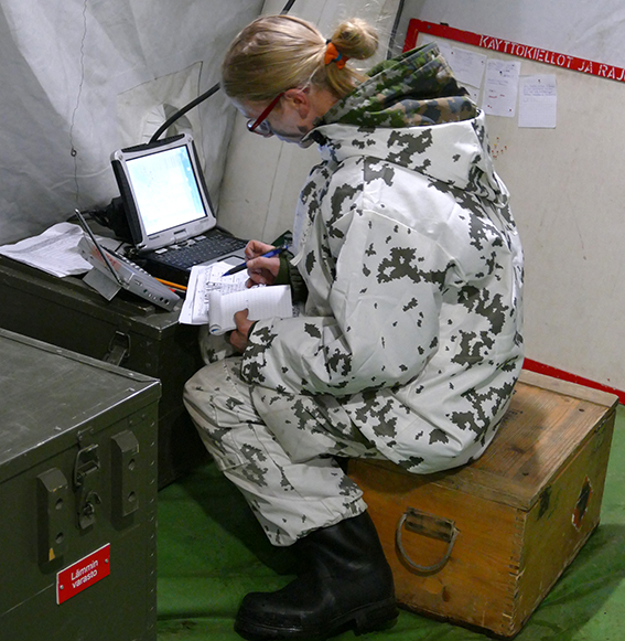 A female soldier writes notes from a computer