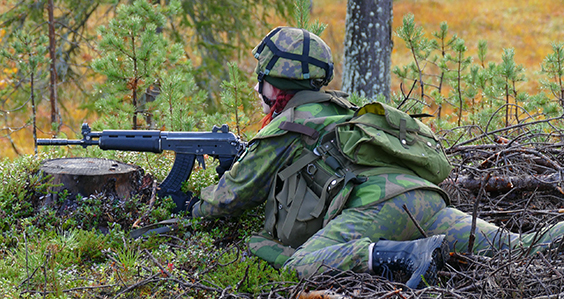 Female soldier lying in the field with an assault rifle.