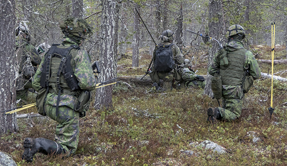 Sotilaat korkeassa polviasennossa metsässä