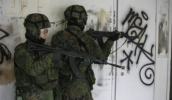 Kaksi sotilasta rynnäkkökiväärien kanssa rakennuksen sisällä