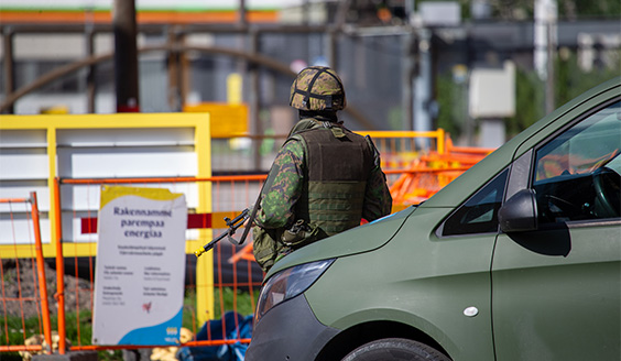 Sotilas ulkona vartiointitehtävässä ja vieressä Puolustusvoimien pakettiauto.