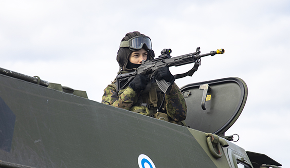 sotilas tähtää aseella miehistönkuljetusvaunun katolta