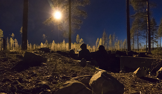 Kaksi sotilasta öisessä metsässä, taivaalla loistaa kirkas valo.