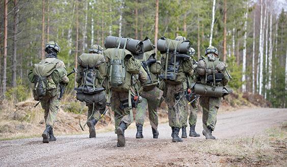 seitsemän sotilasta kävelee maantiellä 