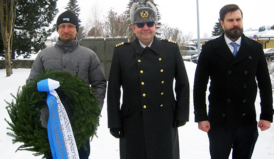 kolme henkilöä laskemassa seppelettä