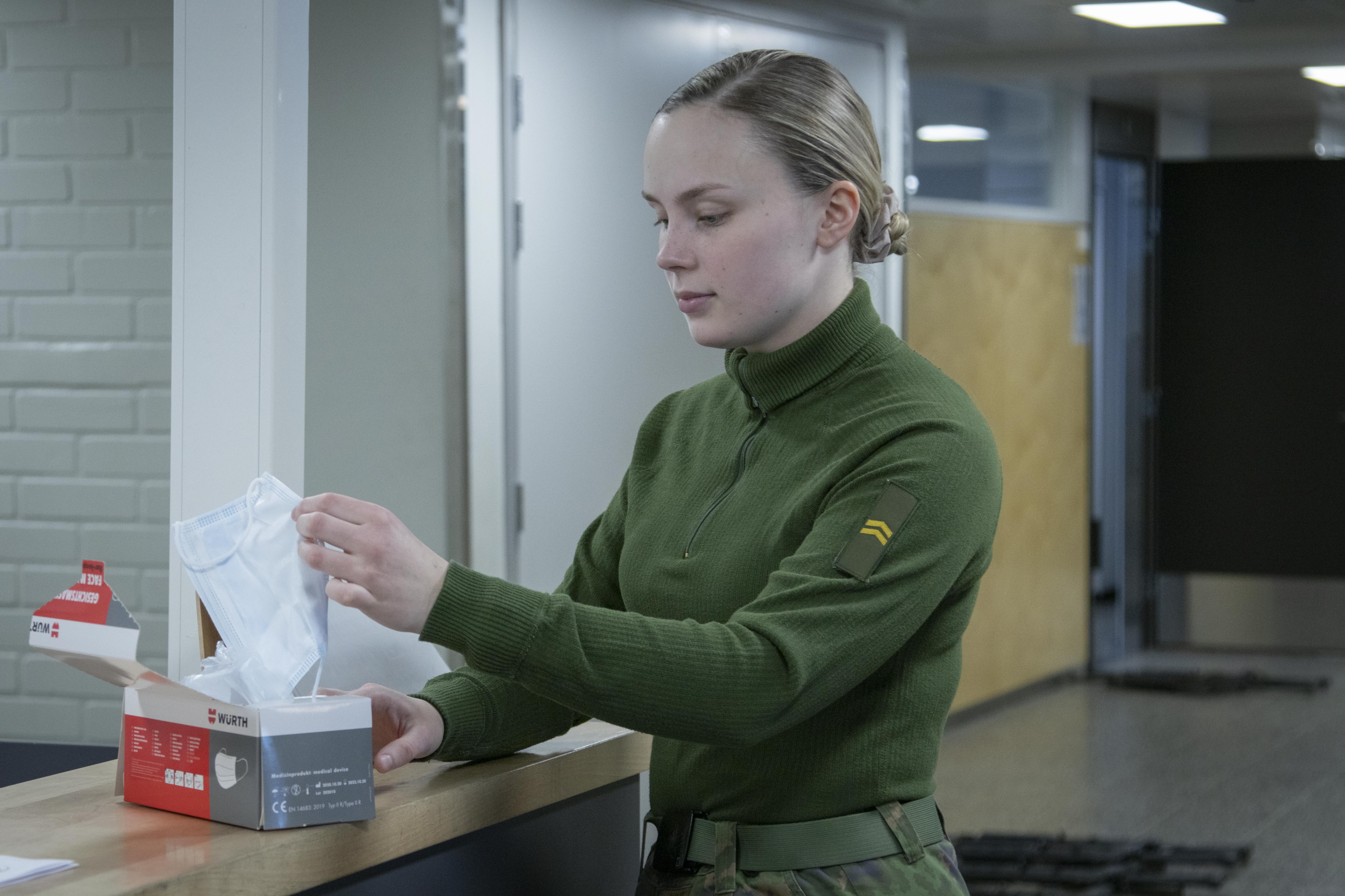 Alikersantti ottaa pahvilaatikosta kasvomaskia itselleen.