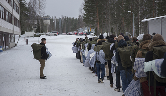 Ihmiset kävelevät jonossa ulkona liinavaatteiden kanssa