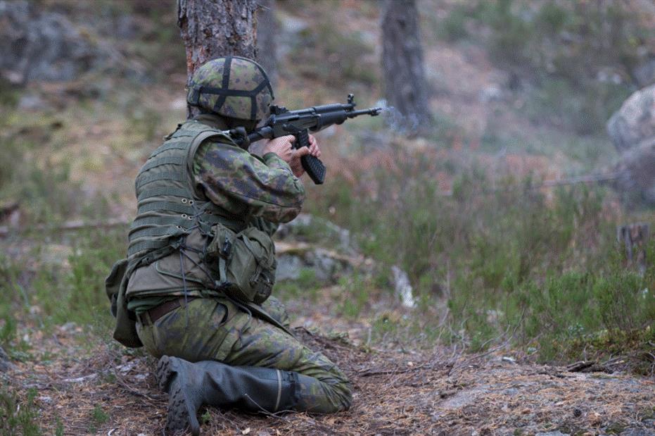 A soldier shoots from behind a tree