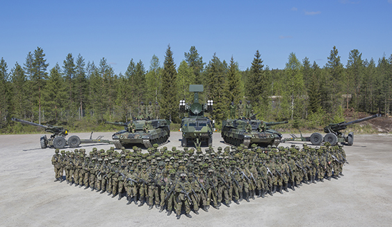 Soldiers in a triangular formation with equipment in the background